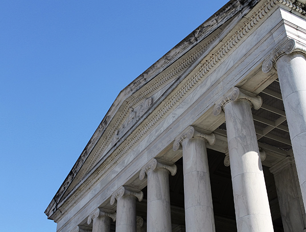 Photograph of a building with columns from below towards the sky